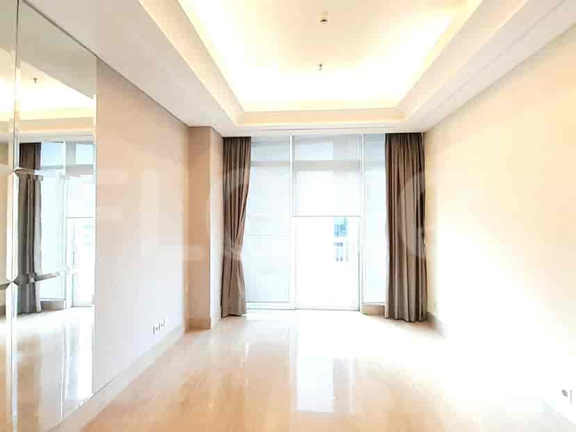 A bright living room with large windows, sheer curtains, and a view of the city.
