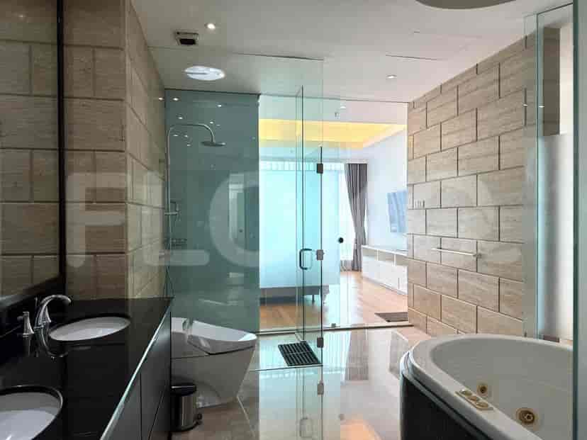A luxurious bathroom with marble tile walls, a walk-in shower, a bathtub, and a double vanity.