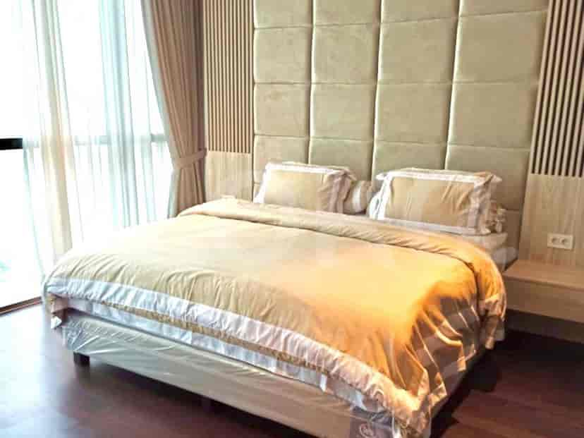 A bedroom with a king-sized bed, a large upholstered headboard, and bedside tables.