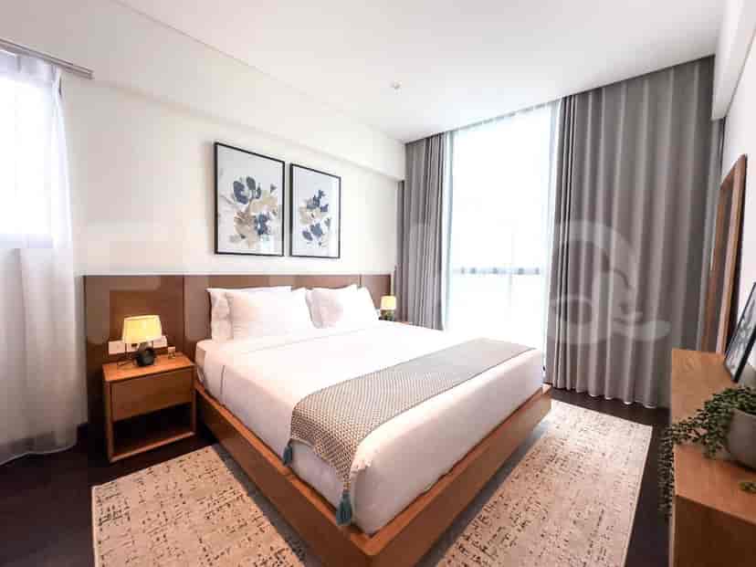 A bedroom with a king-size bed, wooden bedside tables, and large windows with grey curtains.