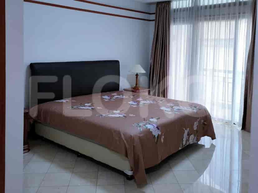 A bedroom with a queen-size bed, nightstand, lamp, and curtains.