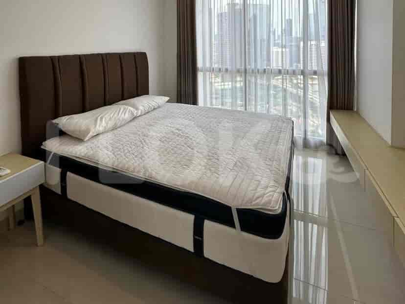 Comfortable bedroom featuring a bed with a headboard and large windows offering city views.