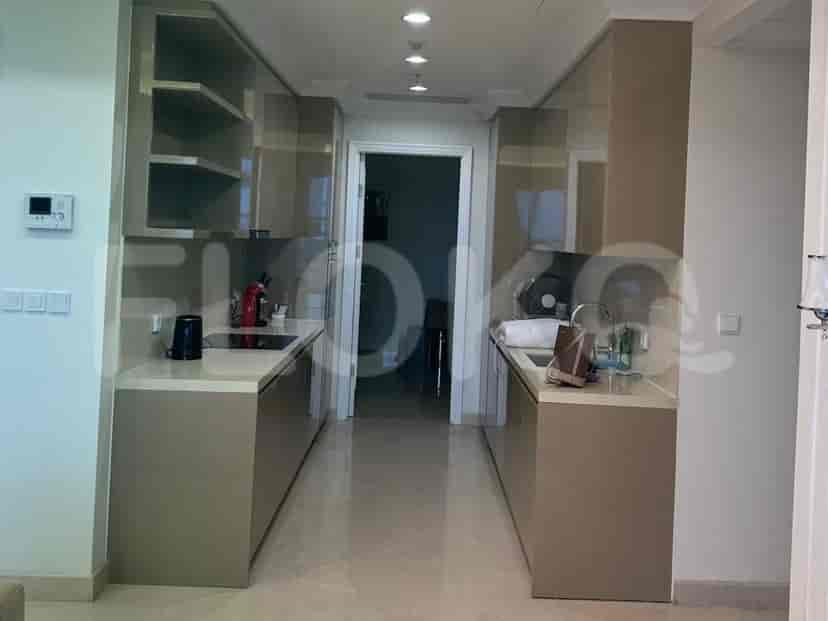 A galley-style kitchen with sleek, light brown cabinetry, countertops, and integrated appliances.
