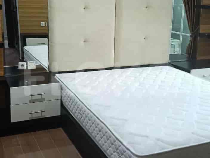 A bedroom with a large bed, a nightstand with drawers, and a mirror reflecting a white mattress.