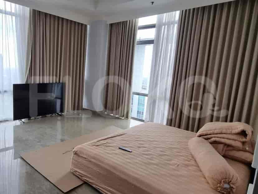 A bedroom with a queen-size bed, a television, and large windows with curtains.