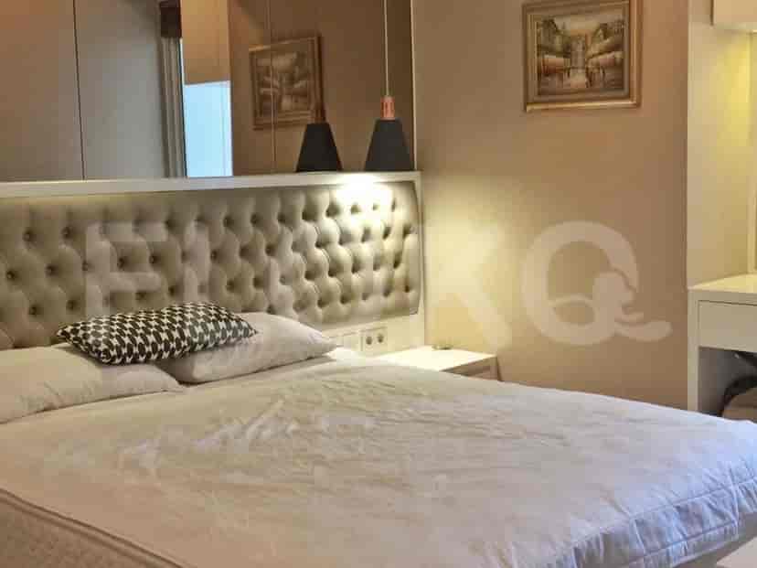 A bedroom with a tufted headboard bed and bedside tables.