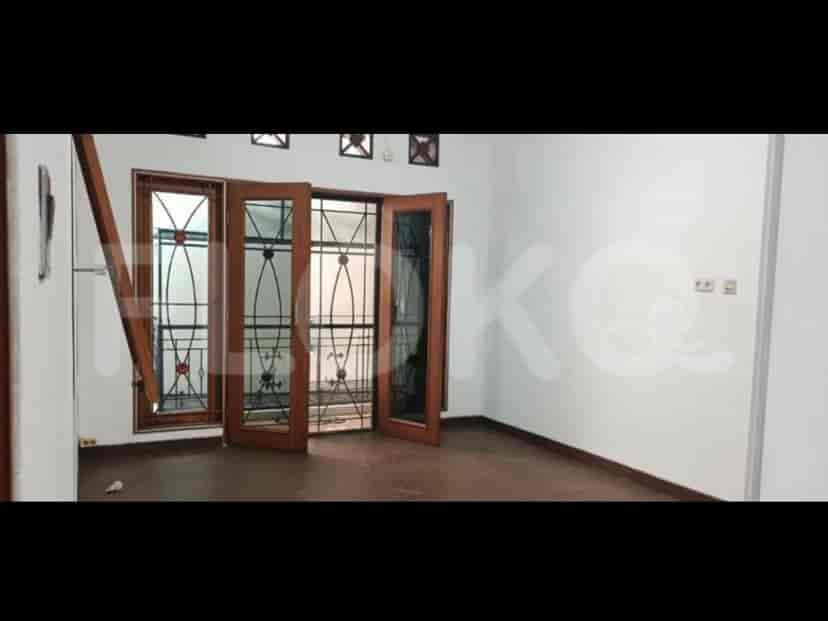 A room with wooden doors and windows, showing a view towards the outside with a brown floor.