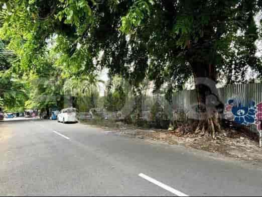 A view down the road with trees and a white car.