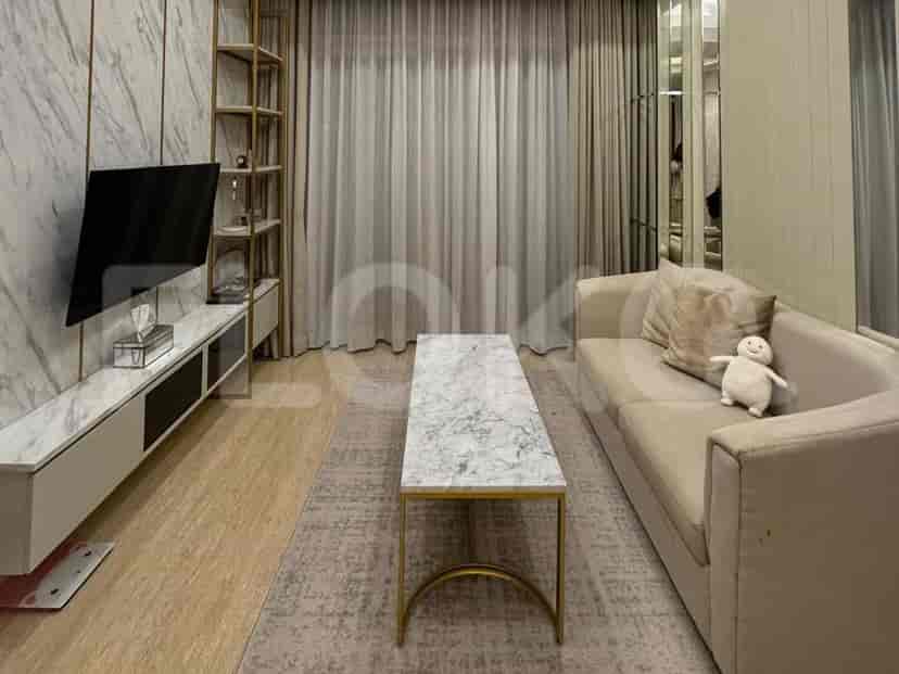 A modern living room with a marble-top coffee table, a beige sofa with a stuffed toy, and a wall-mounted TV.