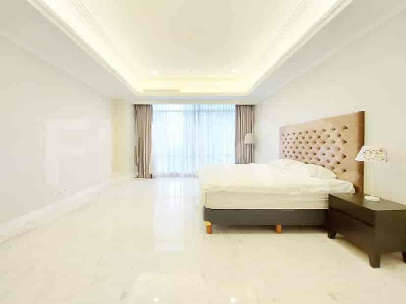 A spacious bedroom with a large bed with a tufted headboard and a large window.