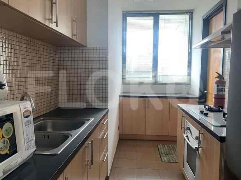 A compact kitchen with dual sinks, wooden cabinets, and a window with blinds.