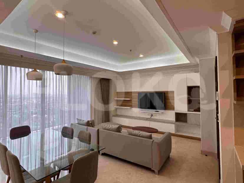 A spacious living room with a large window overlooking the city, a dining table, and a modern entertainment unit.
