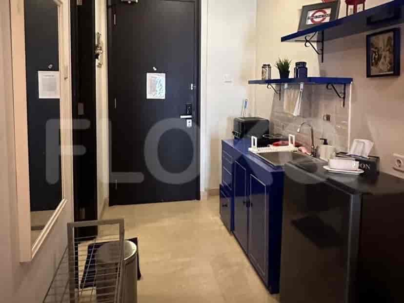 A compact kitchenette with blue cabinets, a sink, a microwave, and a mini-fridge.