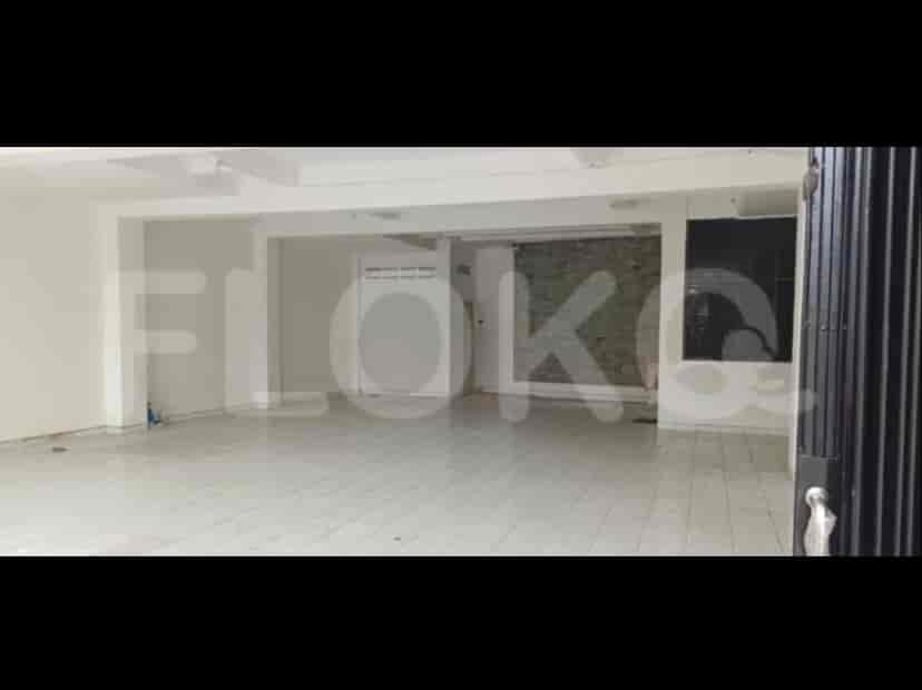 An open space with a white tiled floor, likely a living room or a commercial space. The room is empty.