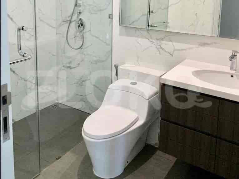 A modern bathroom with a white toilet, marble walls, and a walk-in shower.