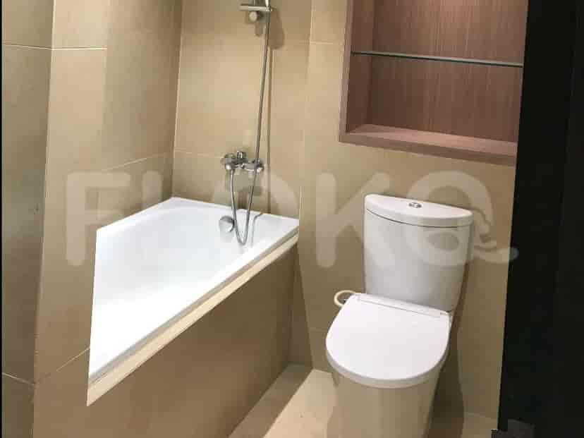 Kamar mandi yang menampilkan bak mandi putih, toilet modern, dan dinding berubin.