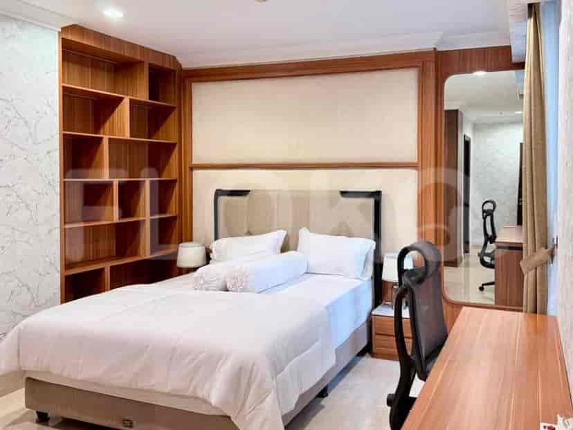 A bedroom featuring a large bed, built-in wooden bookshelves, and a study desk.