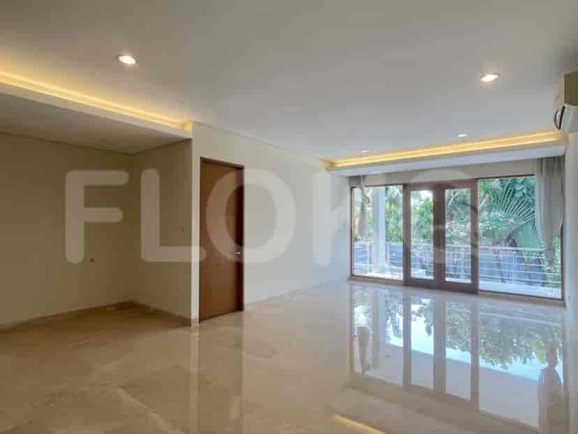 A spacious, light-filled room with cream walls, marble floors, large glass doors leading to a balcony, and modern recessed lighting.