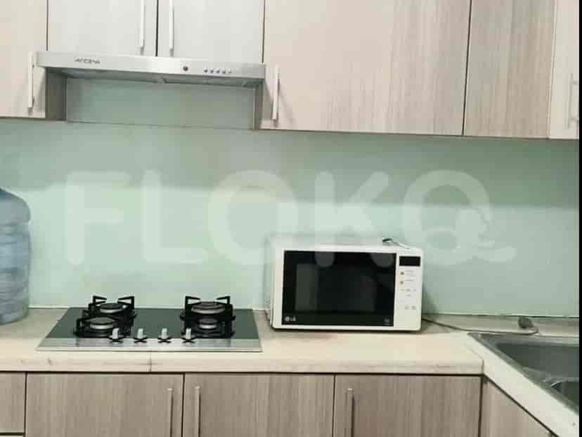 Meja dapur dengan kompor gas, microwave, dan wastafel.