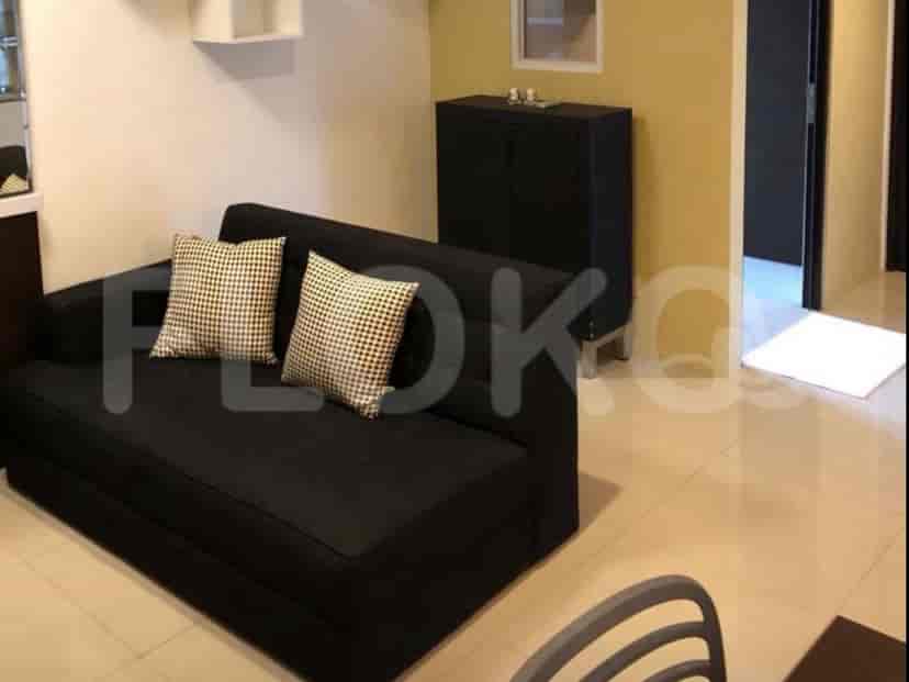 Ruang tamu yang ringkas dengan sofa hitam, dua bantal kotak-kotak, dan lemari hitam di dinding kuning.