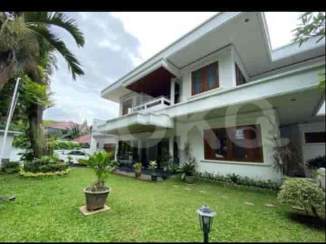 A two-story white house with a well-maintained green lawn, garden, and a small tree.