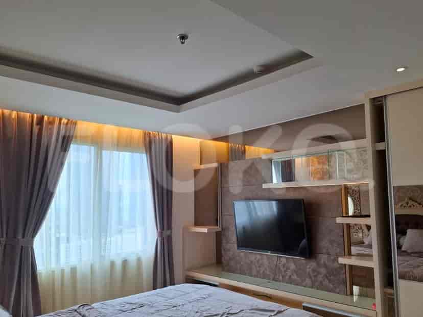 A modern bedroom with a large bed, built-in TV unit, and window.