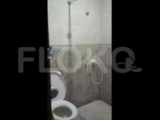 A small bathroom with a Western-style toilet and a handheld shower head.