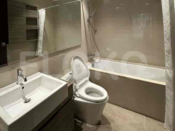 Kamar mandi bersih dengan wastafel, toilet, dan bak mandi, menampilkan dinding berubin krem dan cermin besar.
