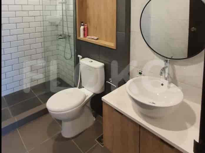 Kamar mandi modern dengan toilet putih dan wastafel.