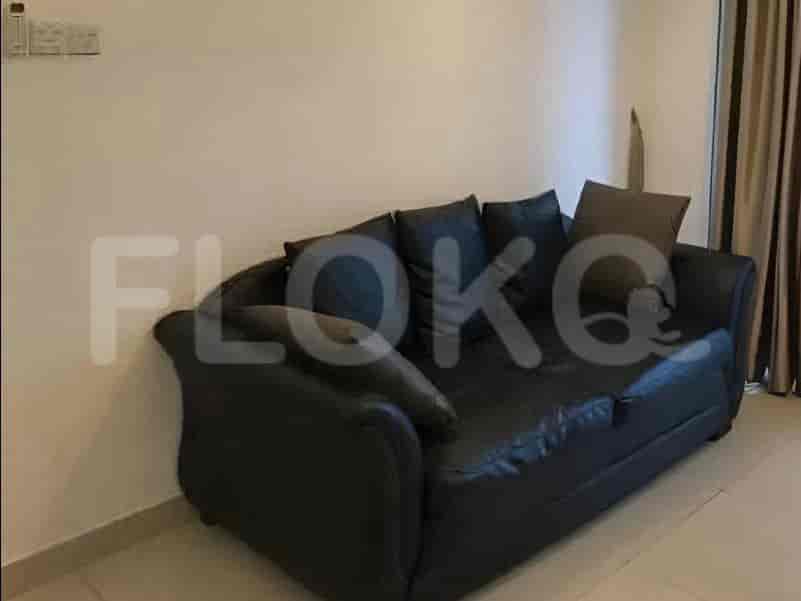 Sebuah sofa kulit gelap dengan beberapa bantal di ruangan berdinding putih.