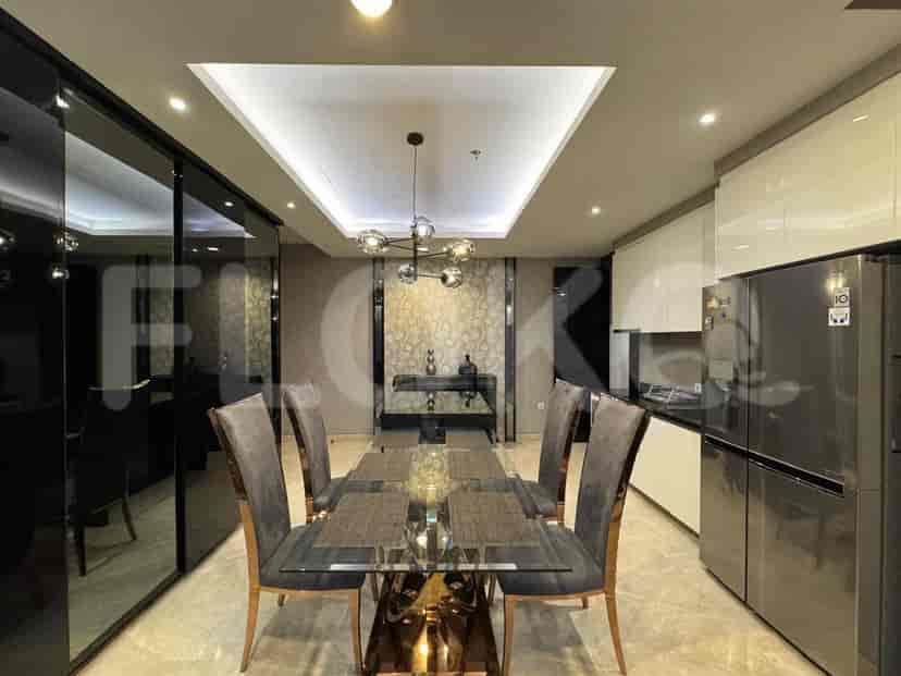 A dining area adjacent to a kitchen, with a glass-top dining table, chairs, and modern kitchen appliances.