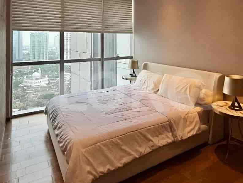 A bedroom with a queen bed, large windows overlooking the city, and minimalist decor.