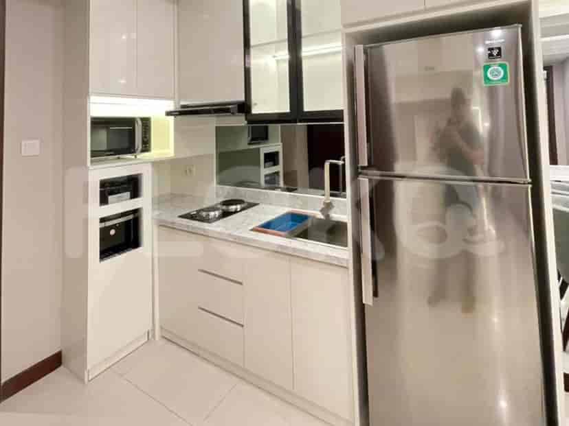 Dapur ringkas dengan peralatan stainless steel, meja marmer, dan lemari putih.