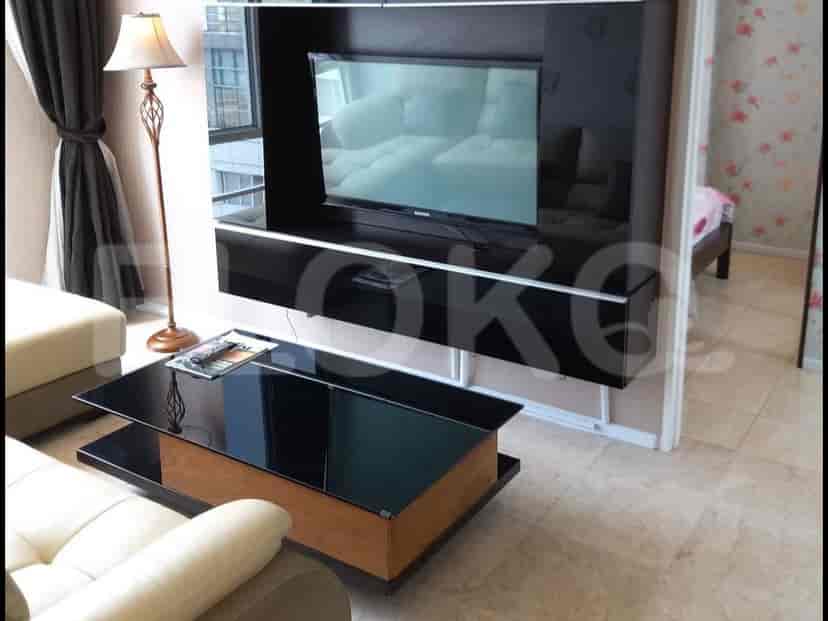 Modern living room with a mounted TV, glass coffee table, and a view into an adjacent room.