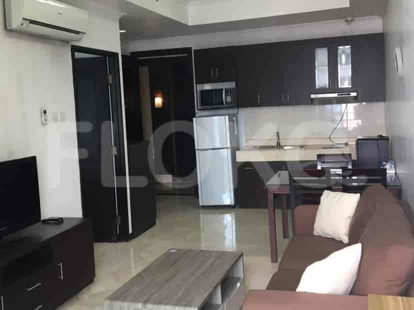 A combined living room and kitchenette area with a sofa, coffee table, TV, dining set, and a compact kitchen.