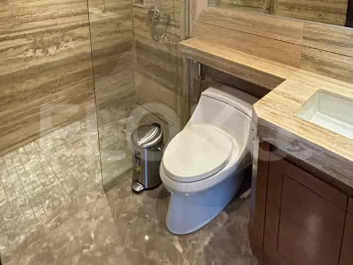 A contemporary bathroom with a toilet, sink, and a walk-in shower with marble walls.