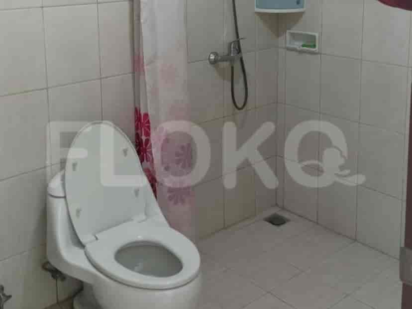 Kamar mandi dengan toilet, tirai shower, dan dinding berkeramik.