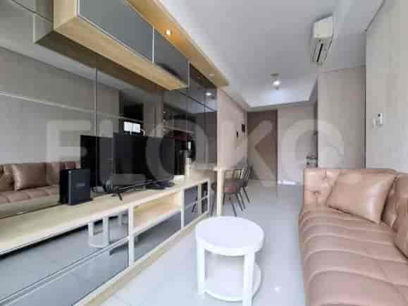 A compact living room with a light-colored sofa, TV console with a TV, and a dining table for two.