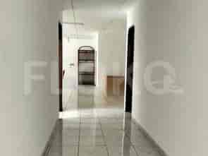 A long, tiled hallway with white walls leading towards a room with shelves.