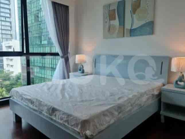 A bedroom featuring a double bed, bedside tables, and large windows.