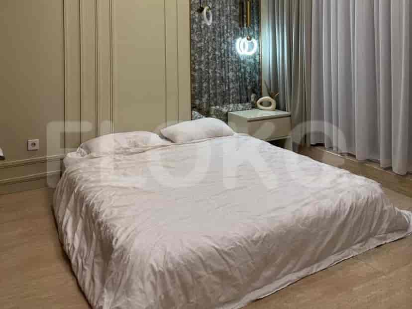 A bedroom with a large bed covered in white linens, a bedside table, and a unique wall feature.