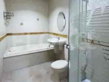 A bathroom with a bathtub, a shower with a glass enclosure, and a toilet.