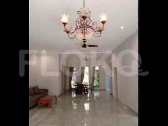 A spacious living room with an L-shaped grey sofa, wall-mounted smart TV, and chandelier.