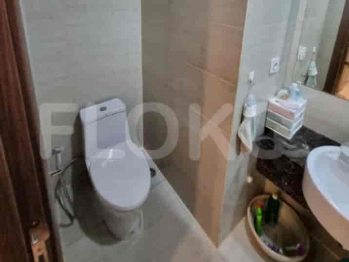 Kamar mandi modern dengan toilet dan dinding ubin.