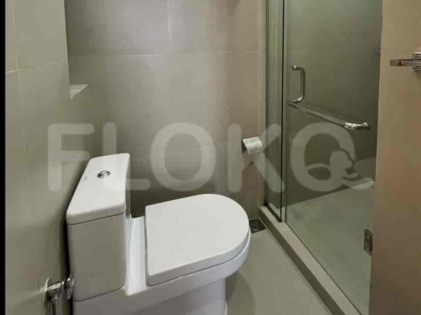 Modern bathroom with a white toilet, glass shower enclosure, and neutral tile flooring.