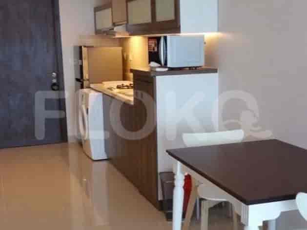 A compact kitchen area with a refrigerator, washing machine, stove, and dining table.