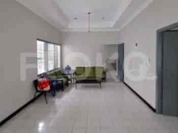 A bright living room with light-colored walls, tiled flooring, and simple furnishings.