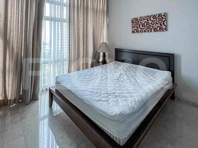 A bedroom with a queen-sized bed, nightstand, and large window with curtains.