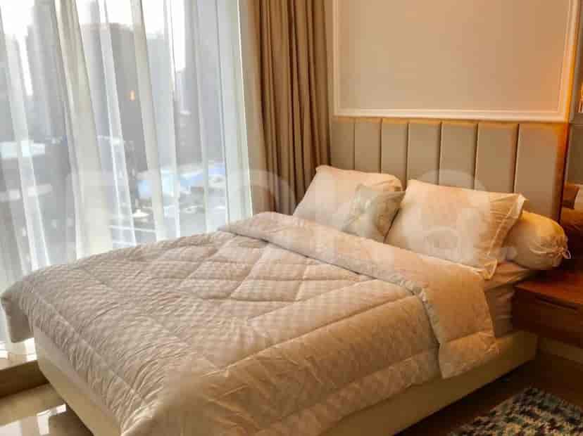 A bedroom with a bed, bedside table, and a large window with a city view.