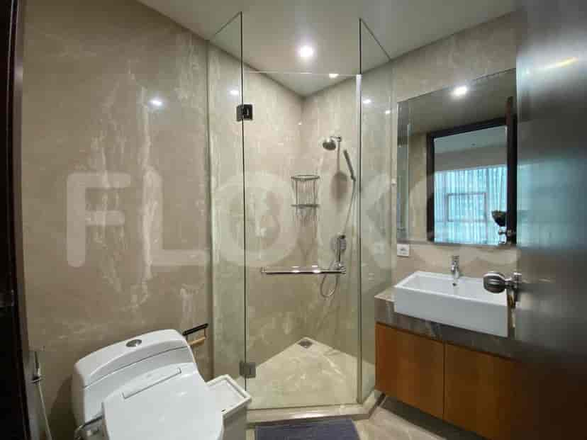 Kamar mandi modern dengan pancuran kaca dan dinding marmer.